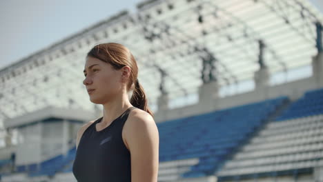 Beautiful-woman-athlete-at-the-stadium-breathing-and-preparing-to-start-the-race.-Motivation-and-tuning-for-the-race.-Concentration-and-attitude